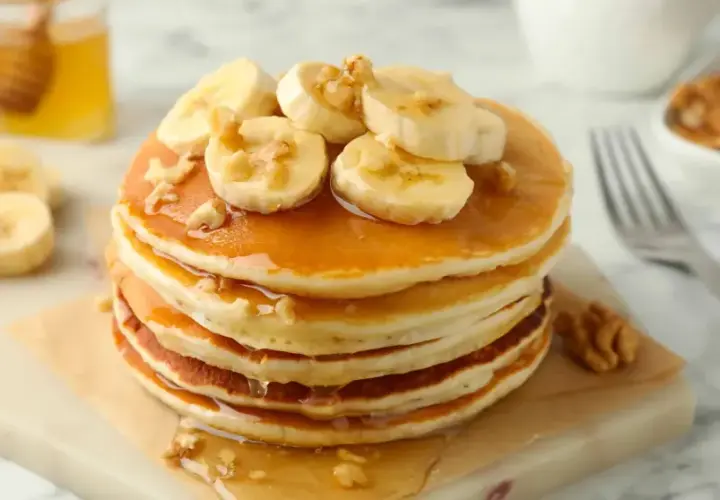 Pancake light con banane e noci, inzuppati nello sciroppo d'acero. Un piacere per gli occhi e per il palato.