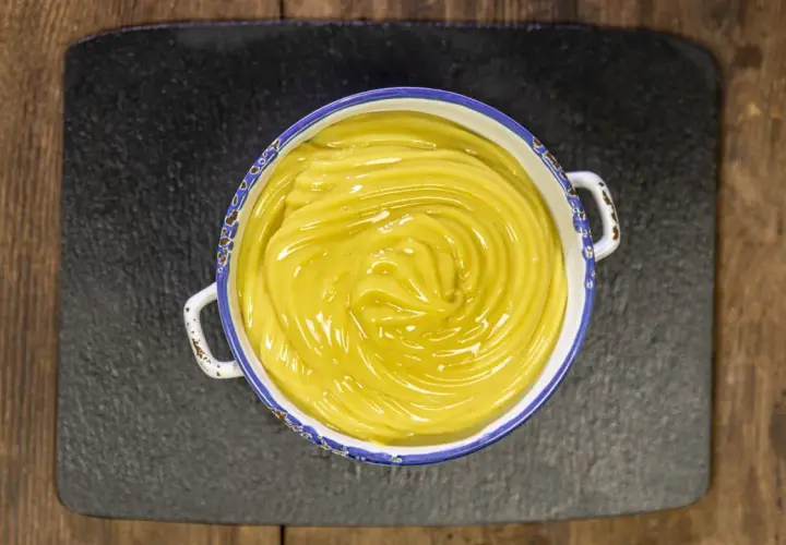 Crema pasticcera vegana, liscia e lucida, in una ciotola con bordo decorato, pronta per farcire dolci.
