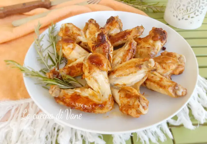 Alette di pollo in padella dorate e succulente, guarnite con rosmarino fresco.