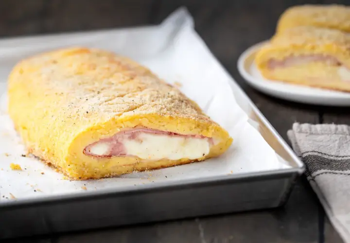 Polpettone di patate ripieno di prosciutto e formaggio filante, dorato e croccante, pronto per essere gustato.