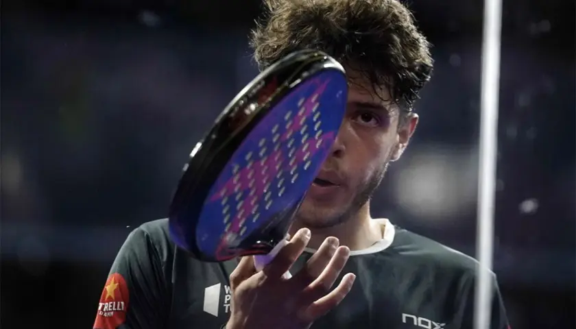 Giocatore di padel con racchetta in primo piano, concentrato. Un punto d'oro per il padel.