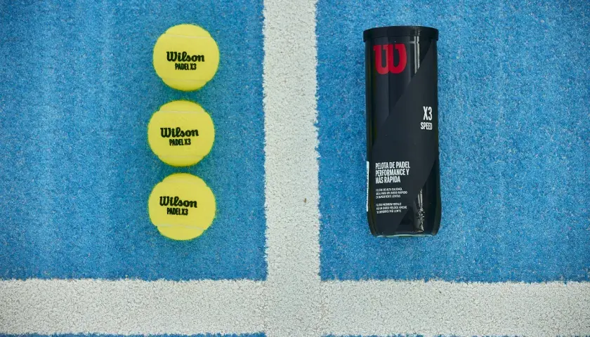 Tre palline da padel Wilson X3 e un tubetto, pronte per una partita veloce sul campo blu.