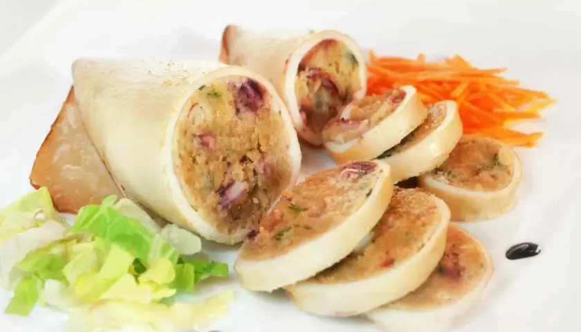 Seppie ripiene, un piatto gustoso con un ripieno ricco e colorato, servite con insalata fresca e carote julienne.