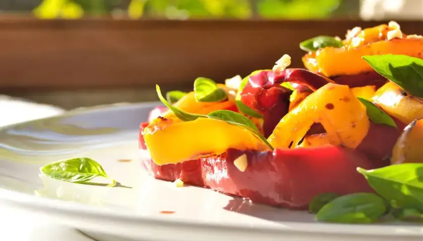 Insalata colorata con peperoni arrostiti, pomodori e basilico fresco. Un'idea gustosa per le tue ricette con peperoni.