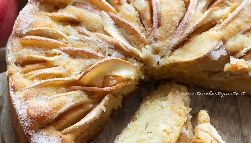 Una deliziosa torta di mele senza zucchero, con fette di mela disposte a raggiera sulla superficie dorata e una spolverata di zucchero a velo.