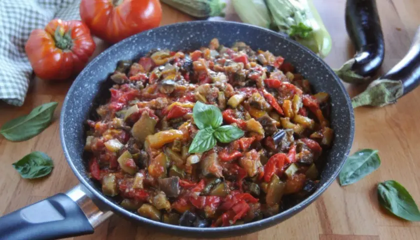 Ratatouille ricetta in padella, con melanzane, zucchine, pomodori e peperoni, guarnito con basilico fresco.