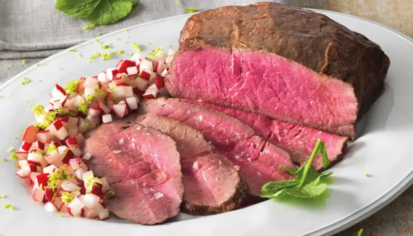 Roast beef ricetta in pentola: succulento e rosato, servito con un contorno fresco di ravanelli e scorza di lime.