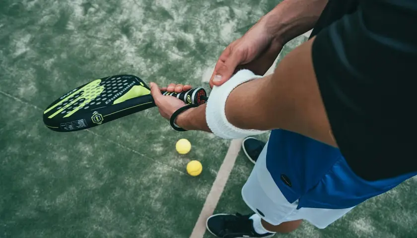 Un giocatore si prepara per una partita di padel negli Stati Uniti, impugnando la racchetta e con le palline a portata di mano.