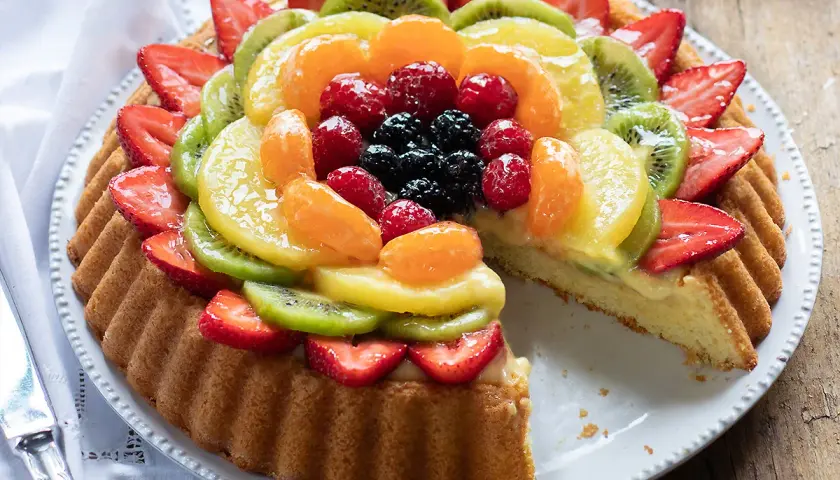 Una crostata morbida alla frutta, con fragole, kiwi, mandarini e frutti di bosco, su una base di crema pasticcera.