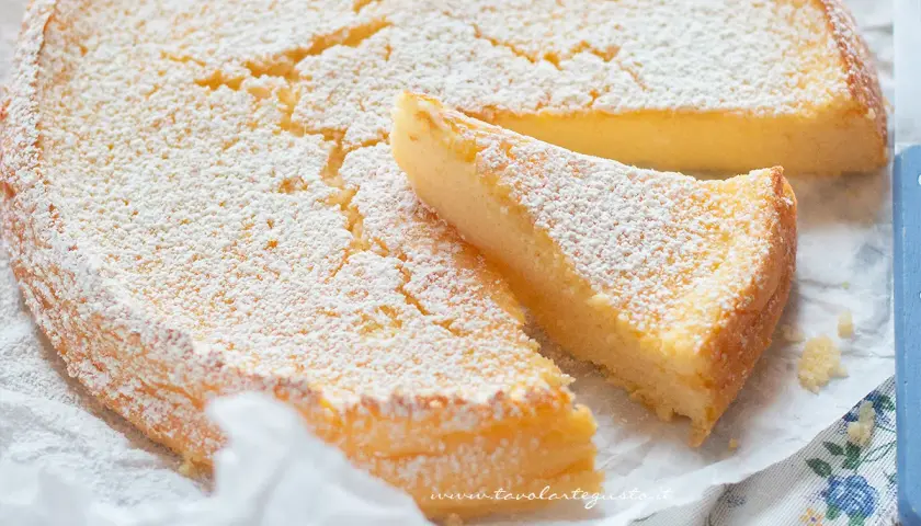 Deliziosa torta ricotta e limone, cosparsa di zucchero a velo, con una fetta tagliata.