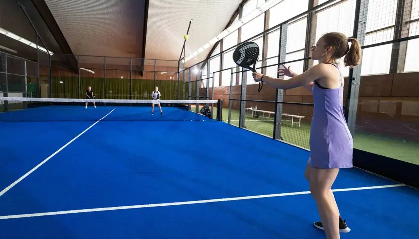 Ragazza in campo da padel 1 vs 1, pronta a colpire la palla.