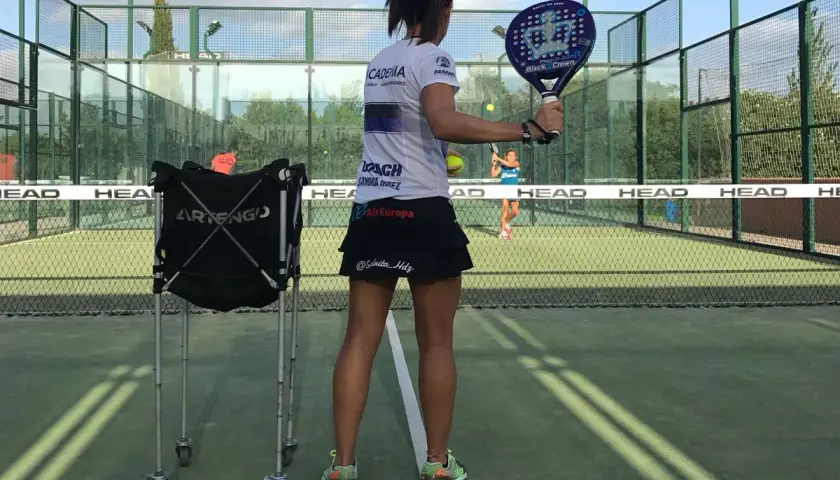 Allenamento intensivo per il corso istruttore padel. Una giocatrice si prepara a colpire la palla su un campo da padel.