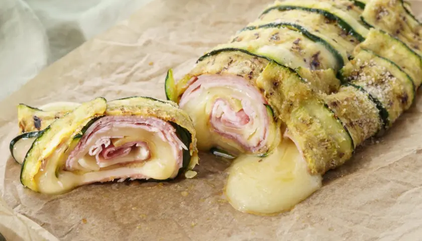 Delizioso rotolo di zucchine con prosciutto e formaggio filante, una ricetta gustosa e leggera.