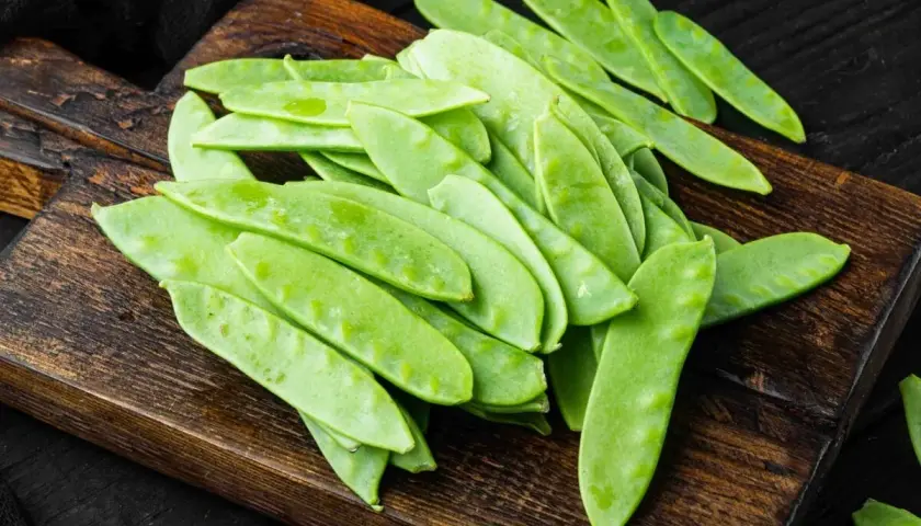 Taccole fresche su tagliere di legno, pronte per gustose ricette primaverili.