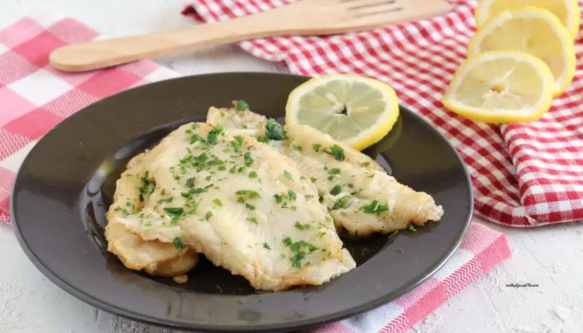 Deliziosa platessa alla mugnaia, dorata e profumata, guarnita con prezzemolo fresco e spicchi di limone.