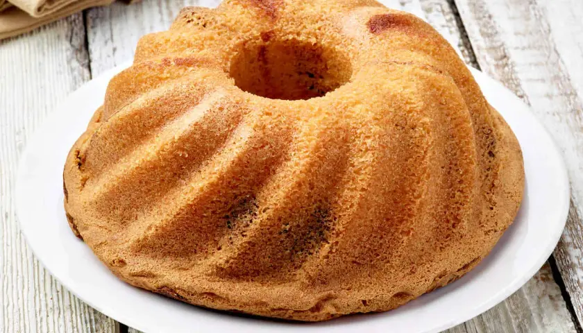 Ciambellone senza uova dorato e soffice, con la sua forma a ciambella, pronto per essere gustato.