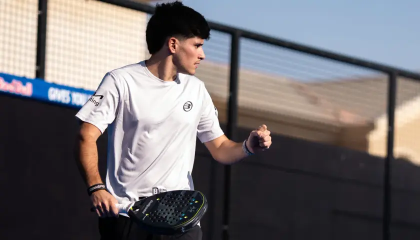 Maxi Sanchez, concentrato, con racchetta da padel in mano, esulta sul campo.