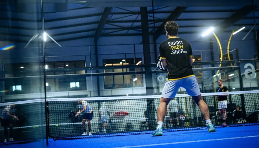 Giocatore di padel in azione, con la scritta "Esprit Padel Shop" sulla maglia. La partita è intensa, ma lui non è una dormilona al padel.