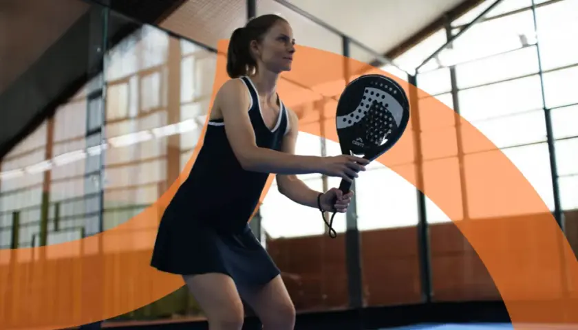 Donna gioca a padel, concentrata sul colpo. Impara i trucchi padel principianti per migliorare il tuo gioco.