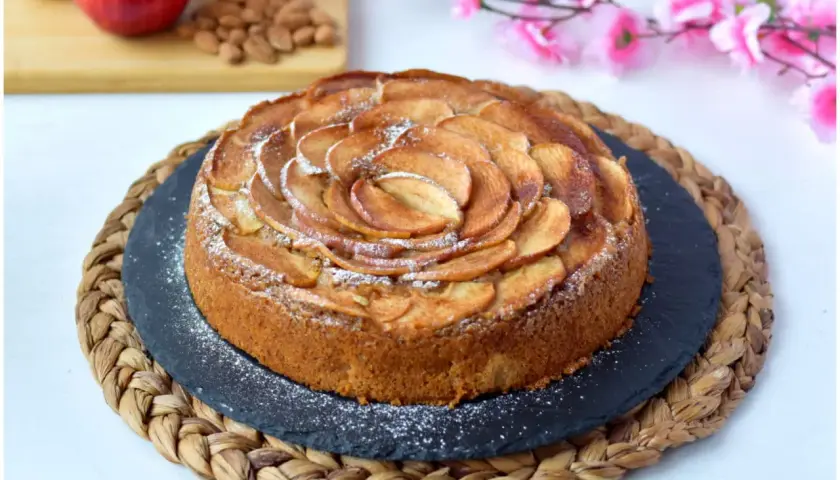 Deliziosa torta di mele vegana, decorata con fettine di mela disposte a spirale e spolverata di zucchero a velo.