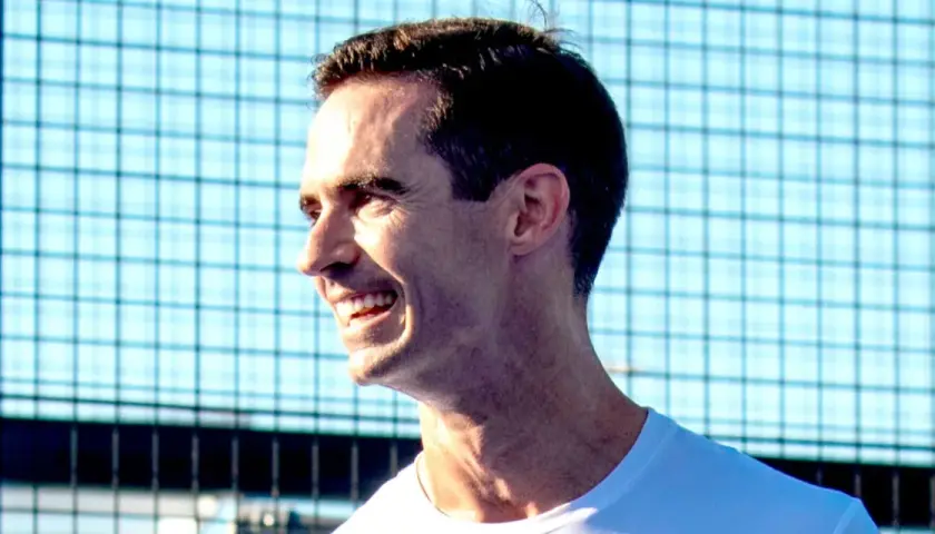 Un uomo sorride con entusiasmo, pronto per una partita di padel.