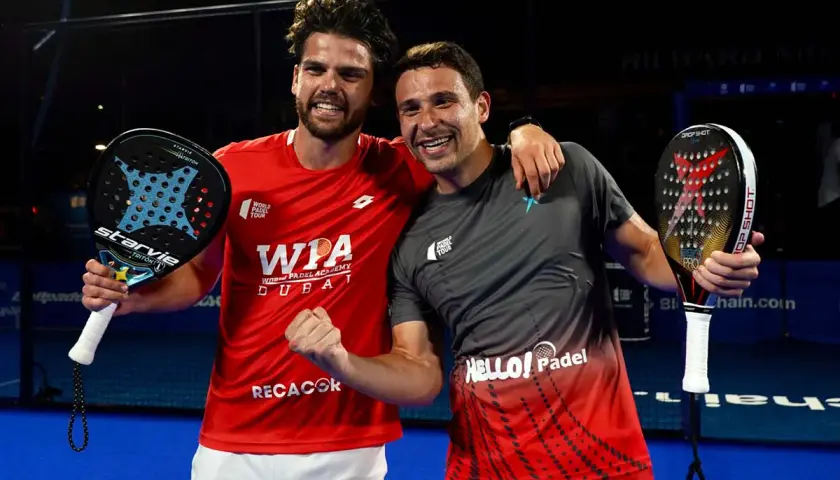 Lucas Campagnolo e il suo compagno festeggiano una vittoria nel padel, sorridenti con le racchette in mano.