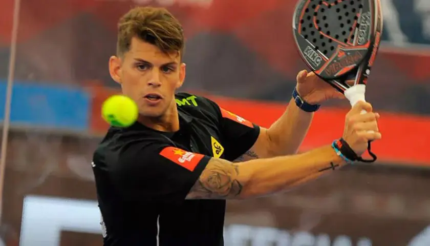Giocatore di padel con racchetta in mano, pronto a colpire la palla. La sua maglia nera ha un logo che ricorda un cobra rosso.