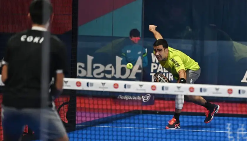 Giocatore di padel in maglia verde colpisce la palla, con un avversario di spalle. Il **chiquita significato** in questo sport è un colpo basso e angolato.