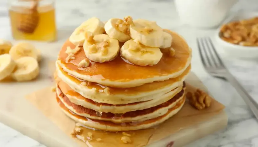 Pancake light con banane e noci, inzuppati nello sciroppo d'acero. Un piacere per gli occhi e per il palato.