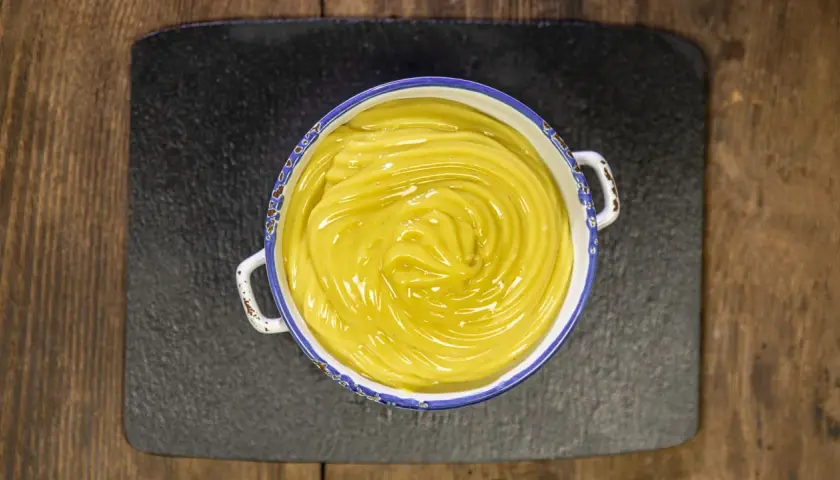 Crema pasticcera vegana, liscia e lucida, in una ciotola con bordo decorato, pronta per farcire dolci.