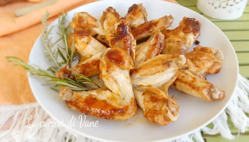 Alette di pollo in padella dorate e succulente, guarnite con rosmarino fresco.