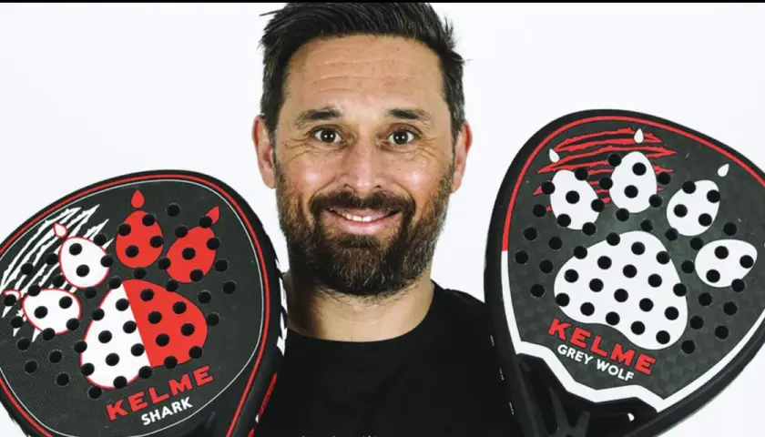 Mati Diaz sorride con due racchette da padel Kelme, una "Shark" e una "Grey Wolf", entrambe con un design a zampa.