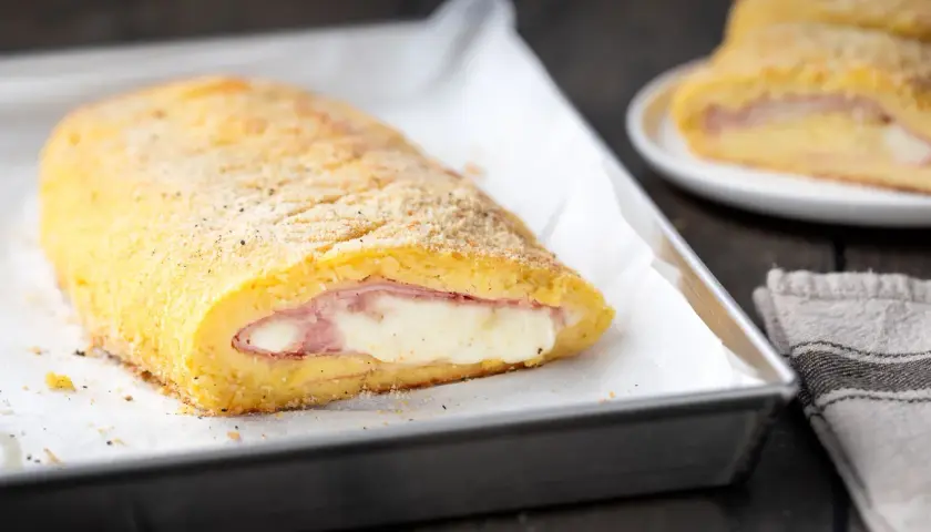 Polpettone di patate ripieno di prosciutto e formaggio filante, dorato e croccante, pronto per essere gustato.