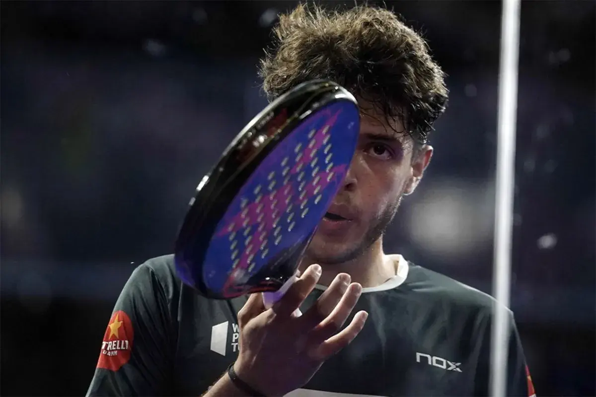Giocatore di padel con racchetta in primo piano, concentrato. Un punto d'oro per il padel.