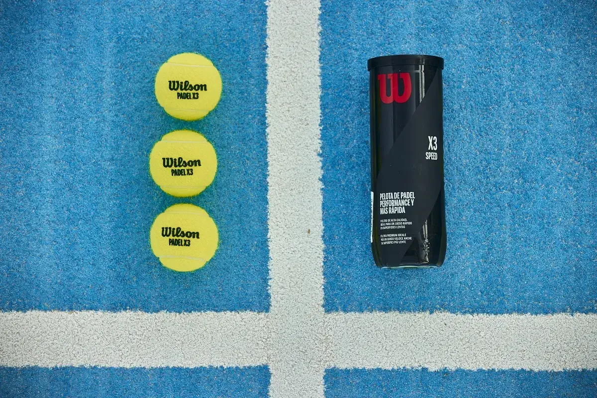 Tre palline da padel Wilson X3 e un tubetto, pronte per una partita veloce sul campo blu.
