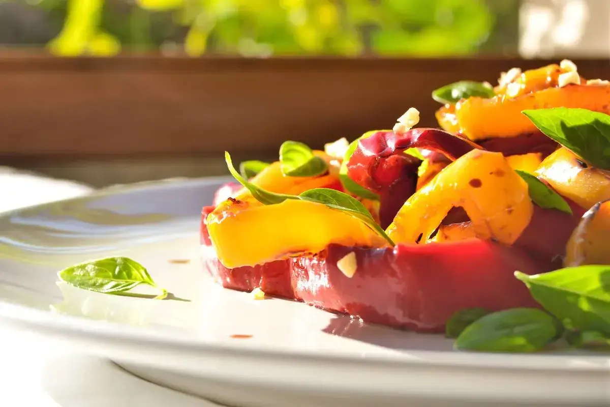 Insalata colorata con peperoni arrostiti, pomodori e basilico fresco. Un'idea gustosa per le tue ricette con peperoni.