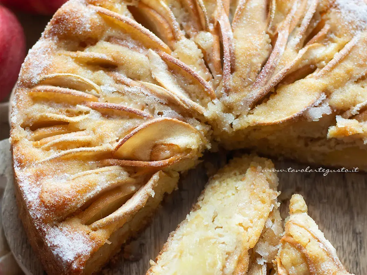 Una deliziosa torta di mele senza zucchero, con fette di mela disposte a raggiera sulla superficie dorata e una spolverata di zucchero a velo.