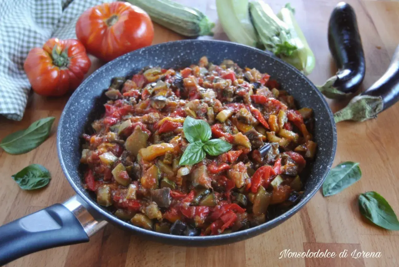 Ratatouille ricetta in padella, con melanzane, zucchine, pomodori e peperoni, guarnito con basilico fresco.