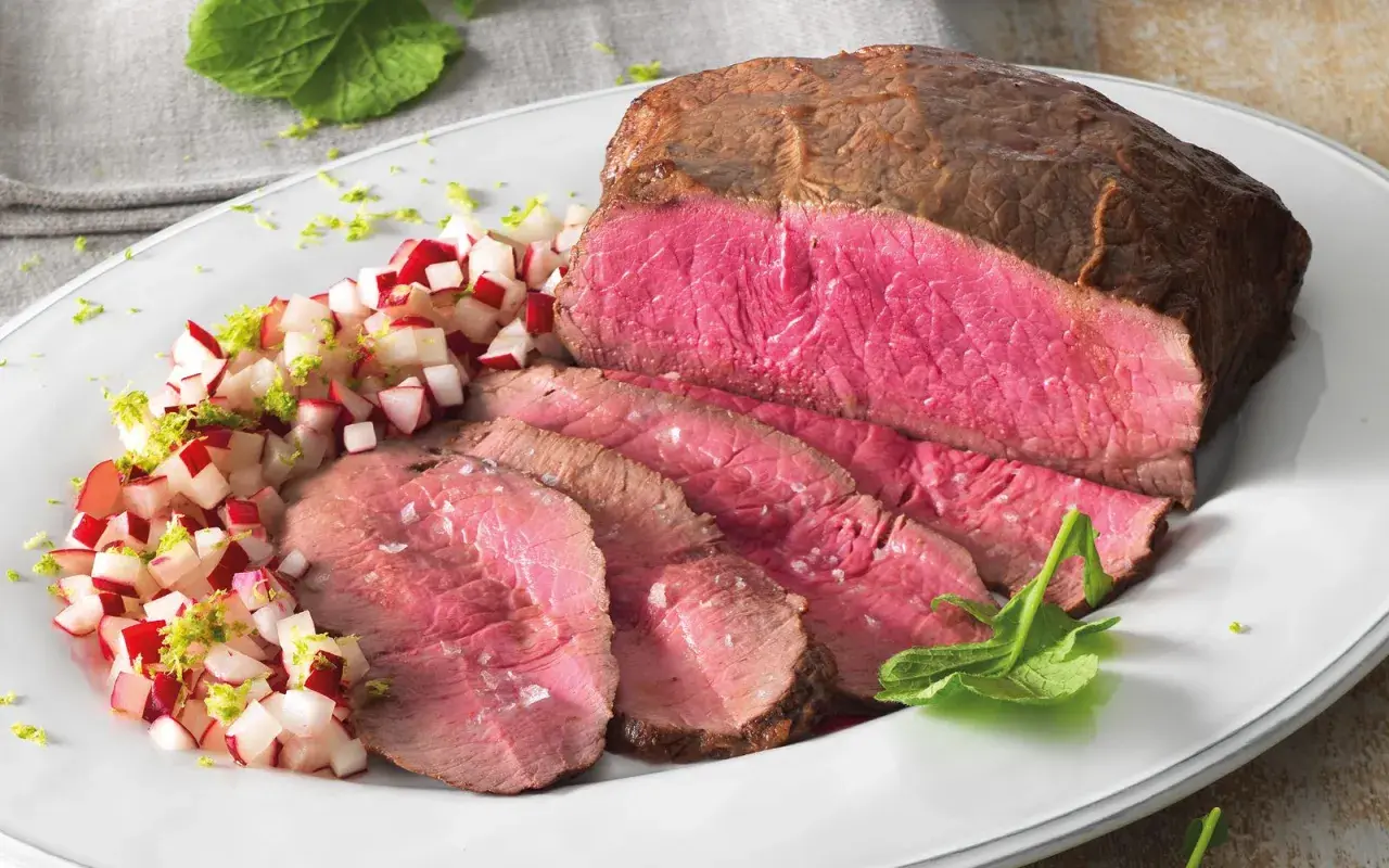Roast beef ricetta in pentola: succulento e rosato, servito con un contorno fresco di ravanelli e scorza di lime.