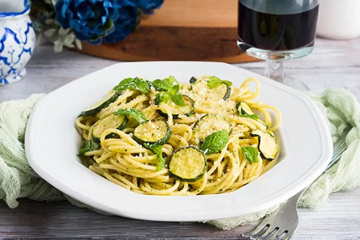 Un piatto di spaghetti con zucchine e menta fresca, un'esplosione di sapori mediterranei. Perfetto per un pranzo leggero e gustoso, questo piatto di pasta e zucchine alla siciliana è un vero piacere per il palato.