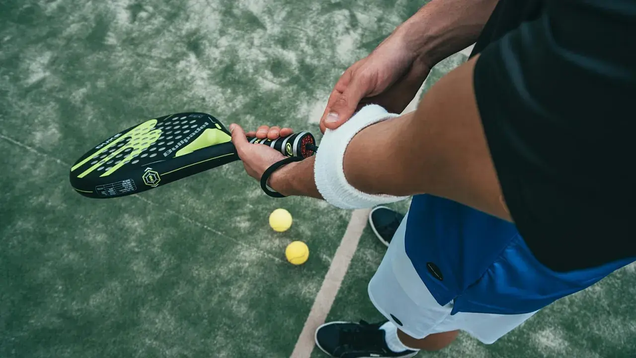Un giocatore si prepara per una partita di padel negli Stati Uniti, impugnando la racchetta e con le palline a portata di mano.