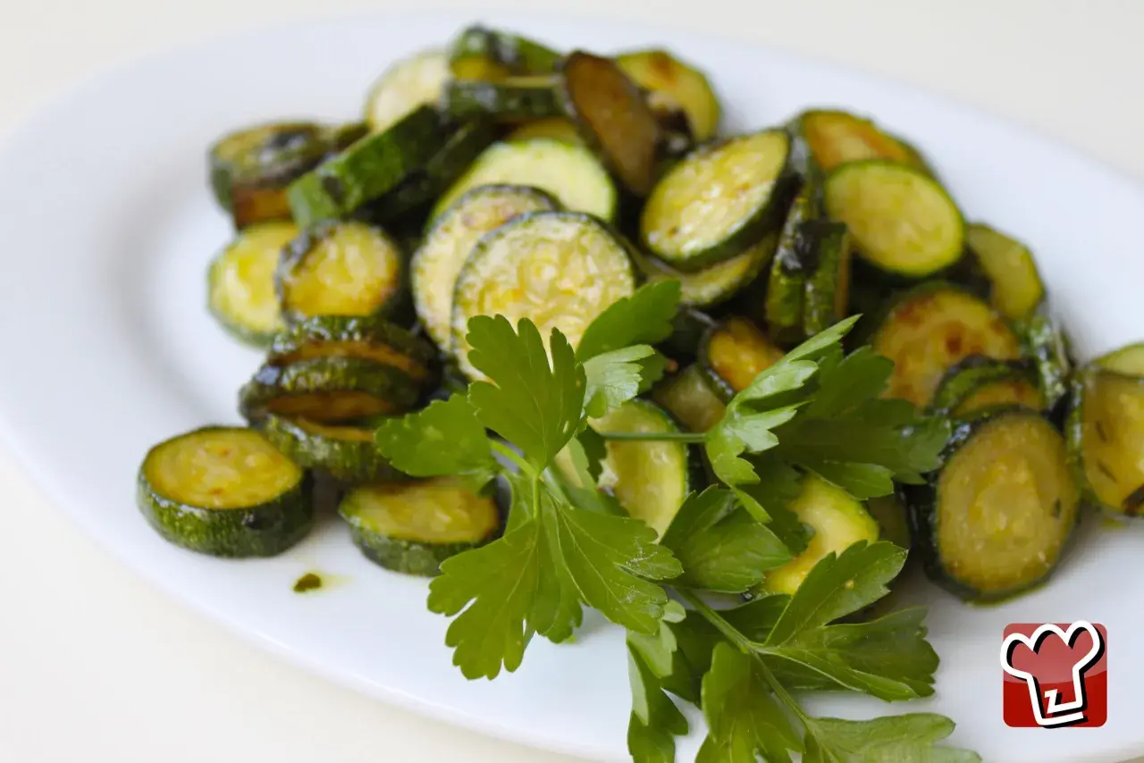 Fette di zucchine saltate in padella, condite con olio e prezzemolo fresco, un classico piatto di zucchine alla poverella.