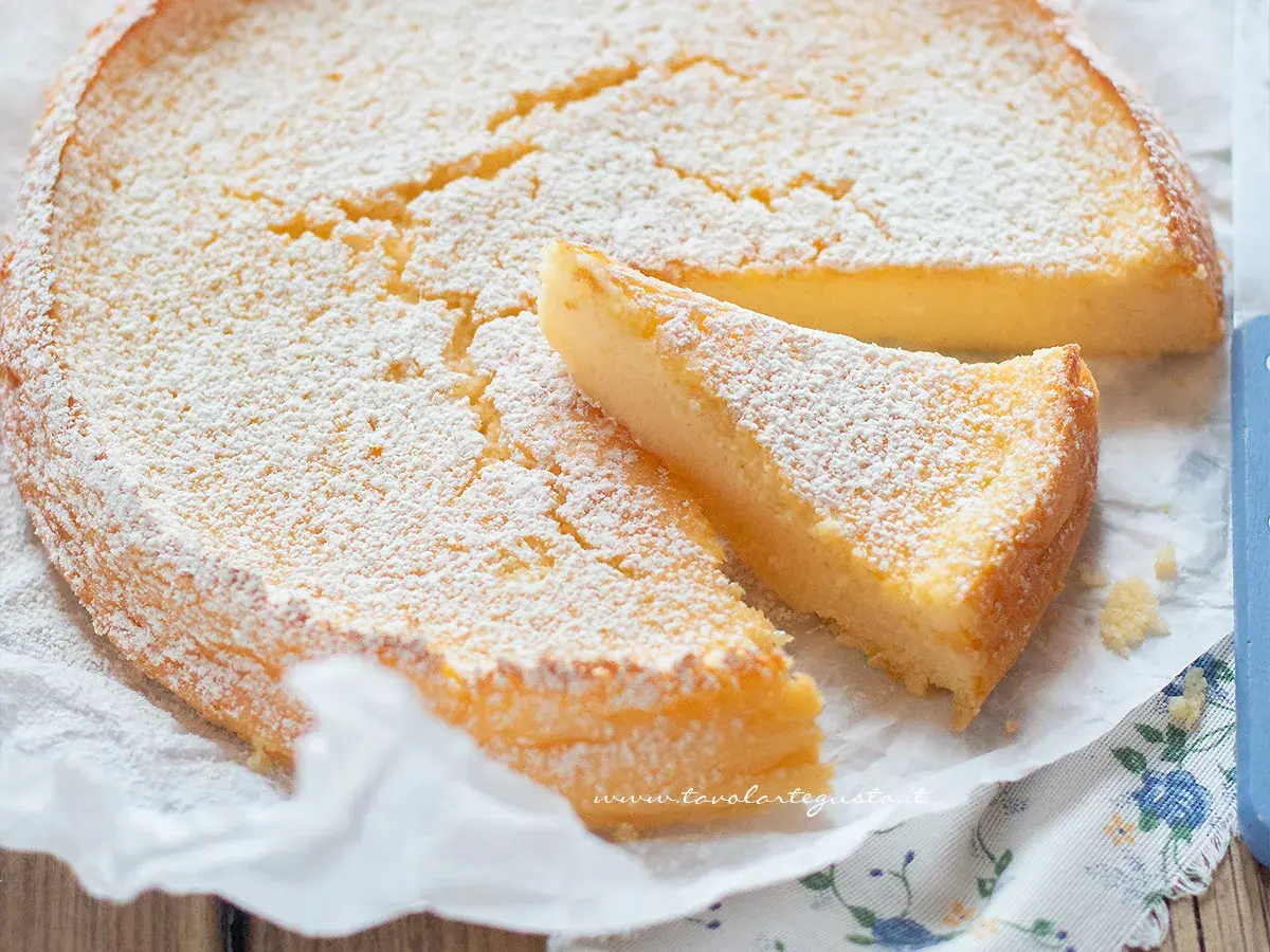 Deliziosa torta ricotta e limone, cosparsa di zucchero a velo, con una fetta tagliata.