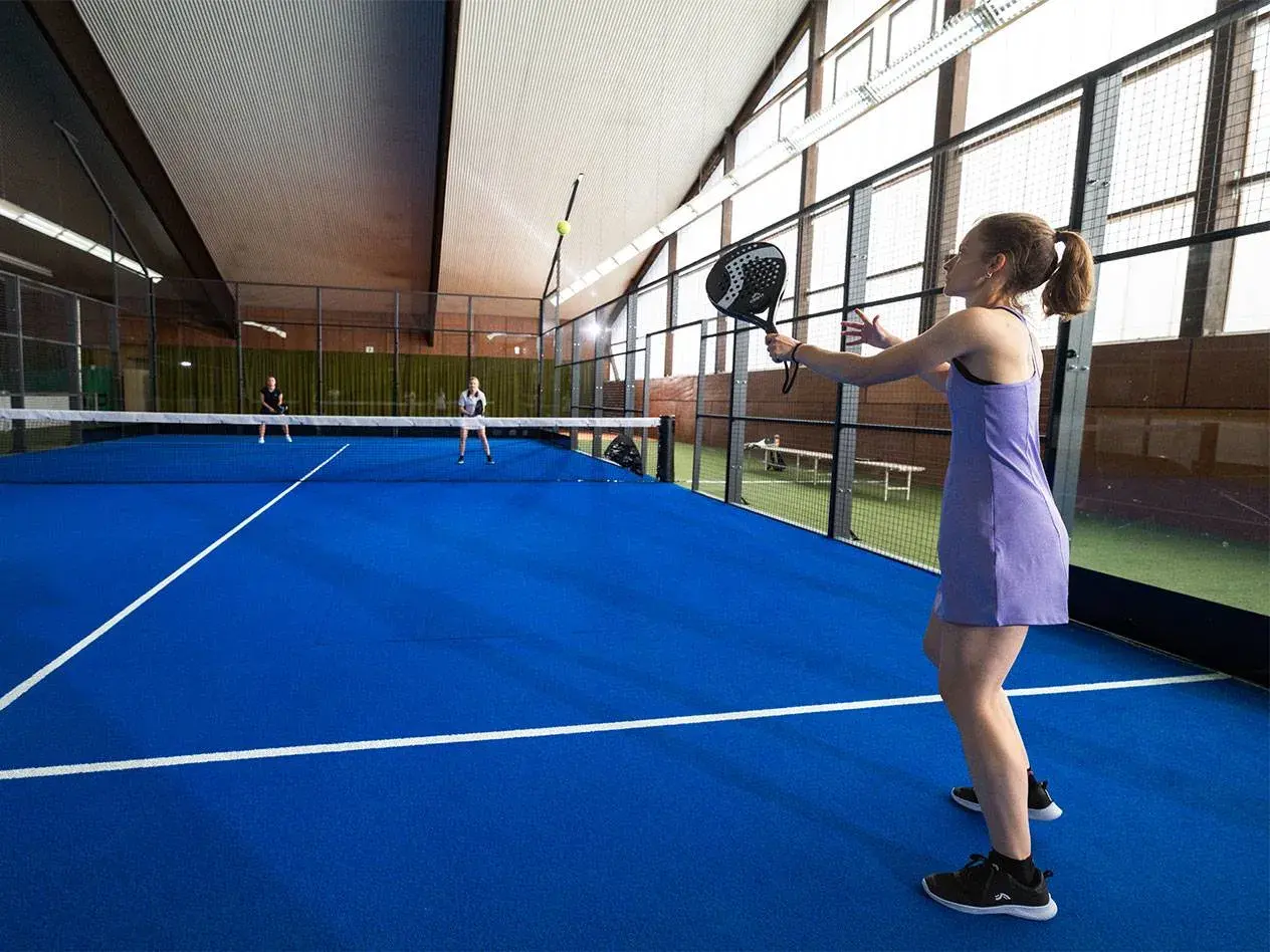 Ragazza in campo da padel 1 vs 1, pronta a colpire la palla.