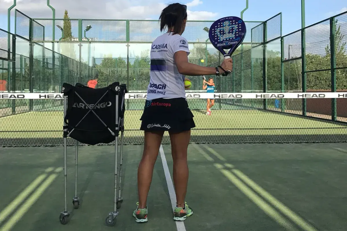 Allenamento intensivo per il corso istruttore padel. Una giocatrice si prepara a colpire la palla su un campo da padel.