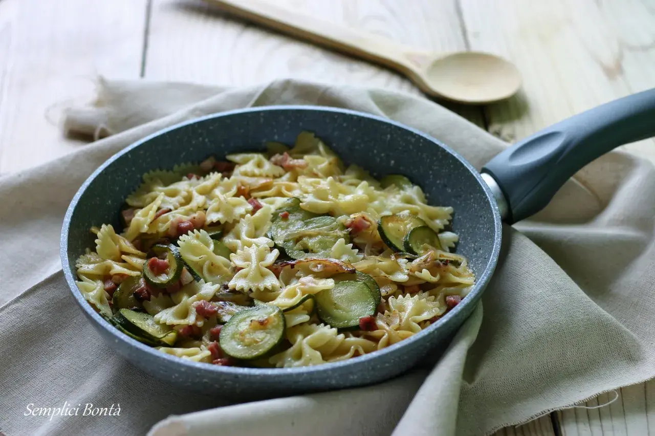 Farfalle con zucchine e pancetta croccante, un piatto semplice e gustoso pronto in padella.