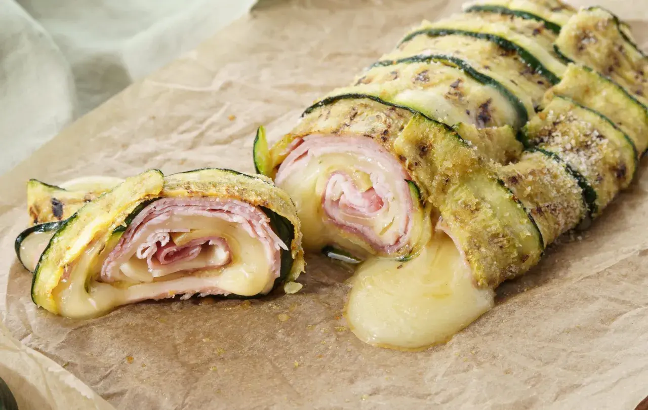 Delizioso rotolo di zucchine con prosciutto e formaggio filante, una ricetta gustosa e leggera.