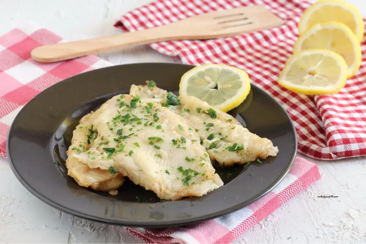 Deliziosa platessa alla mugnaia, dorata e profumata, guarnita con prezzemolo fresco e spicchi di limone.
