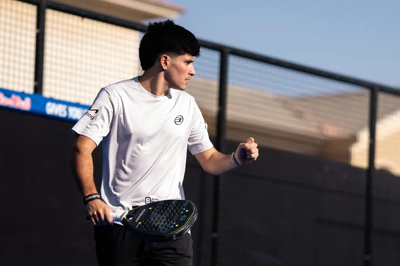 Maxi Sanchez, concentrato, con racchetta da padel in mano, esulta sul campo.