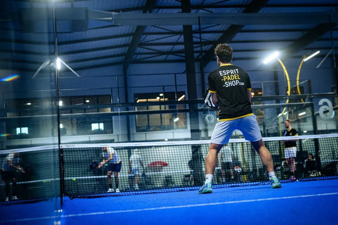 Giocatore di padel in azione, con la scritta "Esprit Padel Shop" sulla maglia. La partita è intensa, ma lui non è una dormilona al padel.